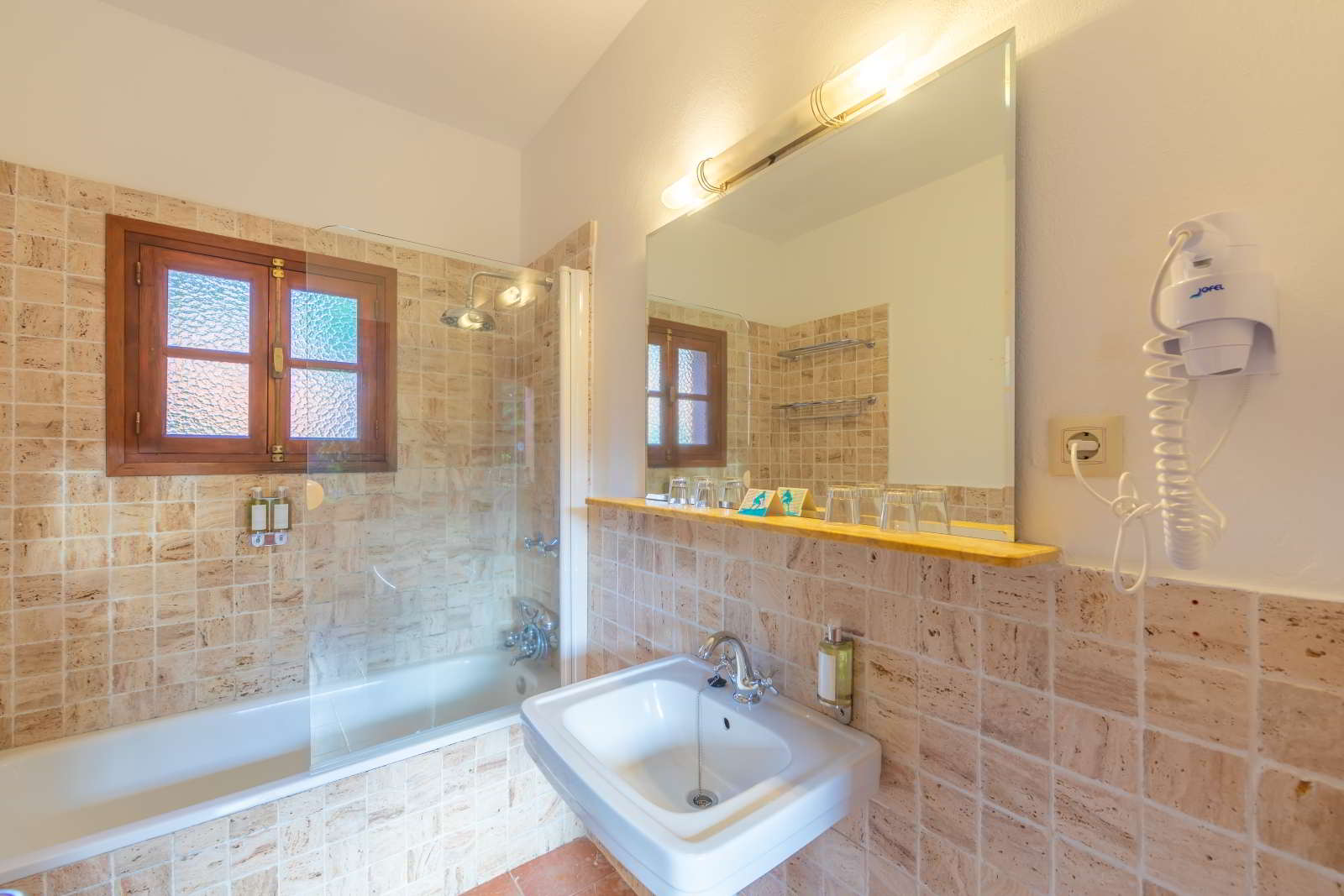 Baño completo con bañera, lavabo y espejo iluminado en la habitación familiar grande del hotel.