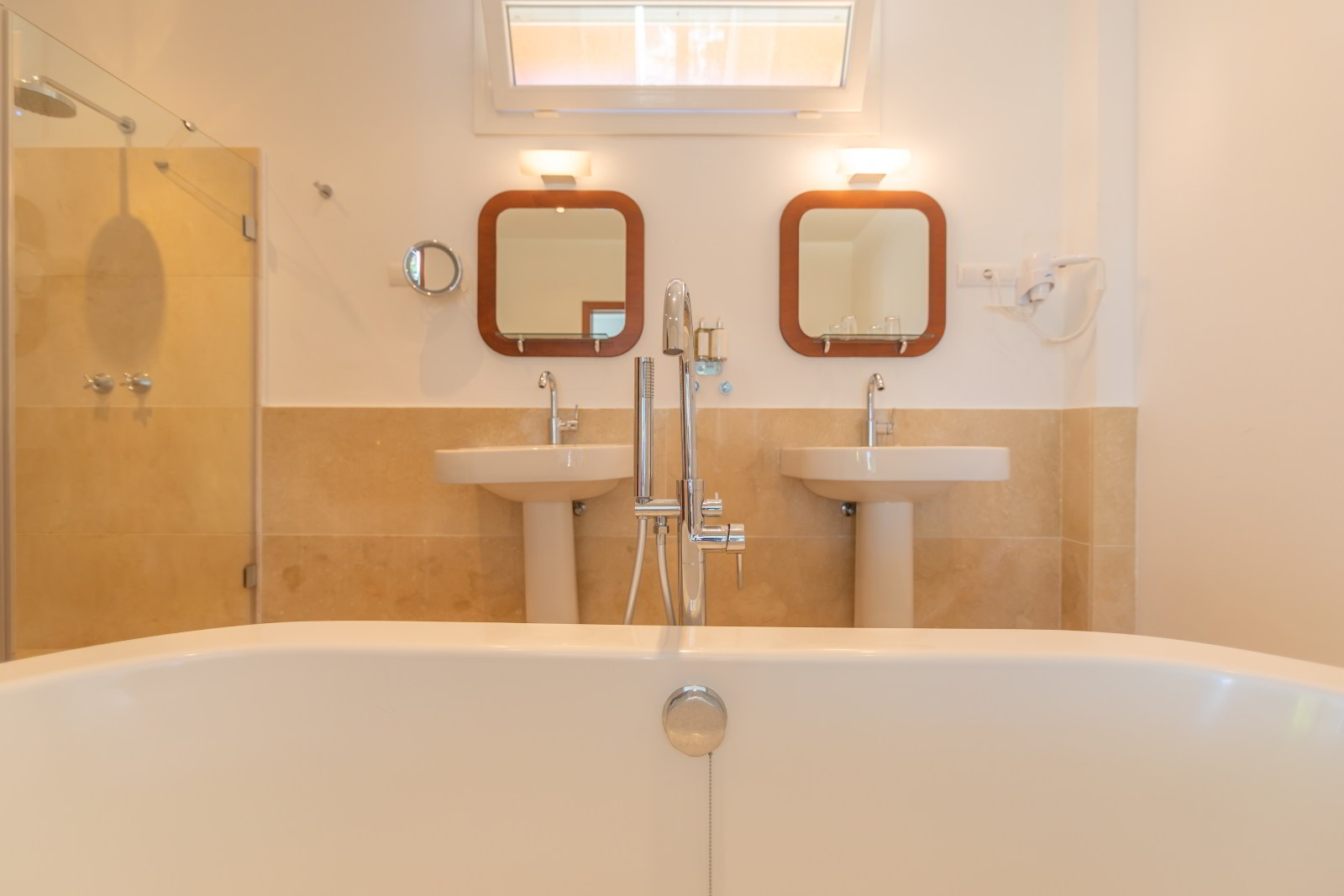 Detalle del baño de habitación junior suite con bañera exenta, doble lavabo y grifería moderna en el Hotel Punta Sur.