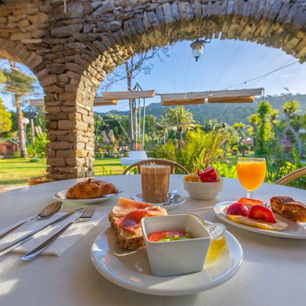 Desayuno servido en mesa exterior bajo un porche de piedra con vistas al jardín del Hotel Punta Sur.