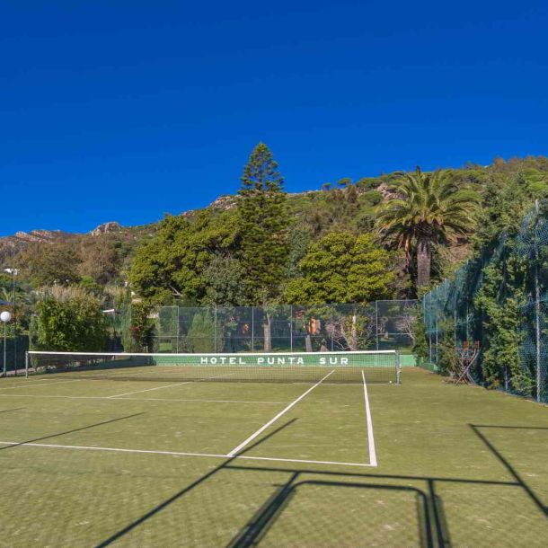 Pista de tenis rodeada de vegetación mediterránea y vistas a la sierra en el Hotel Punta Sur.